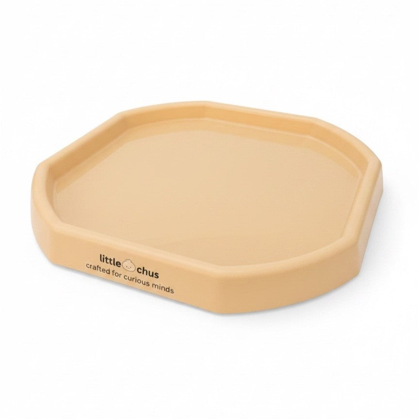 A small octagonal plastic tray in a warm beige color, featuring the text 'little chus crafted for curious minds' printed on one side, set against a plain white background.